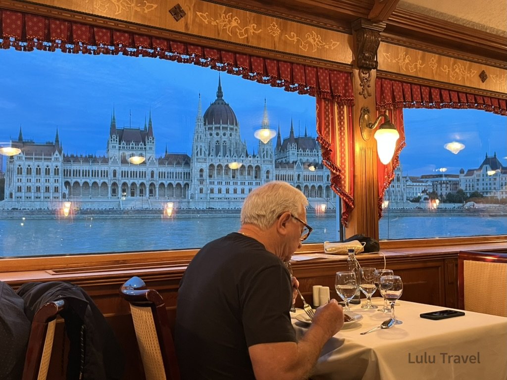 在布達佩斯多瑙河郵輪上用餐，窗外可見夜色中的匈牙利國會大廈