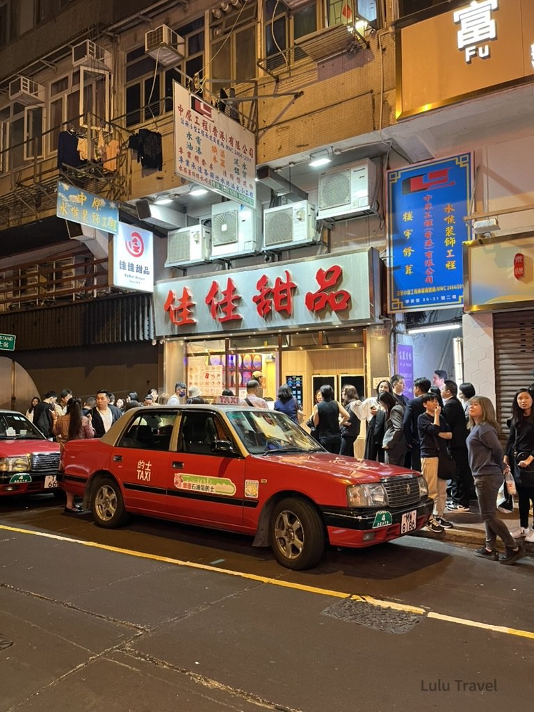 香港佐敦佳佳甜品門口夜景，紅色計程車停在路邊，排隊人潮等待甜品，展現香港夜晚的地道美食文化