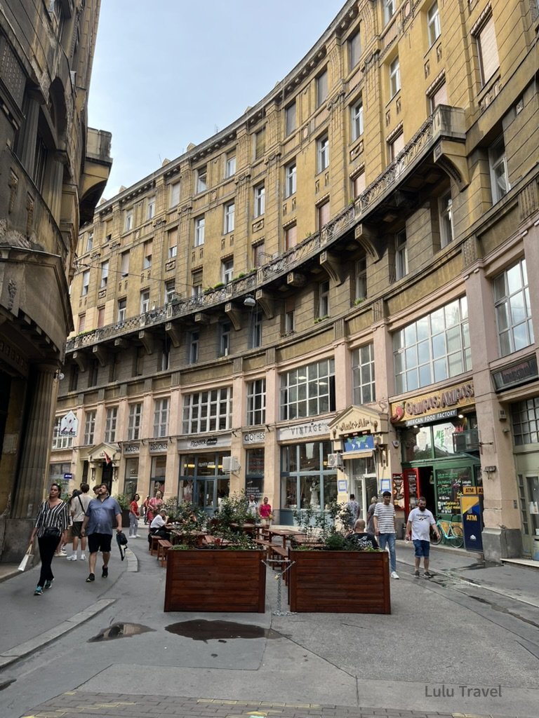 匈牙利布達佩斯市中心街景，弧形歷史建築圍繞廣場，遊客在街區活動