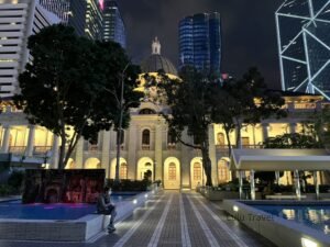 香港旅遊|1 趟香港自由行的每日路線記錄 夜晚燈光下的歷史建築與現代高樓並列,前方廣場有人靜坐,展現城市中舊與新的對比景色