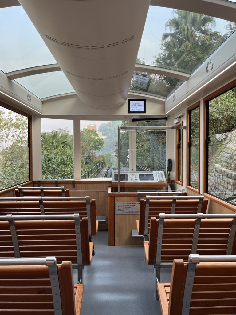 香港太平山纜車車廂內部視角，木質座椅與全景玻璃車頂設計，沿途可欣賞山林綠意與陡坡軌道，是前往太平山頂的經典交通體驗