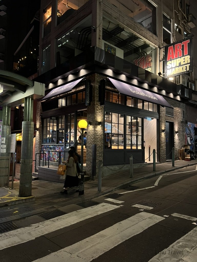 香港夜晚街景，轉角蛋塔店店外觀亮燈營業，結合復古建築與城市霓虹，是中環人氣甜點與散步路線之一