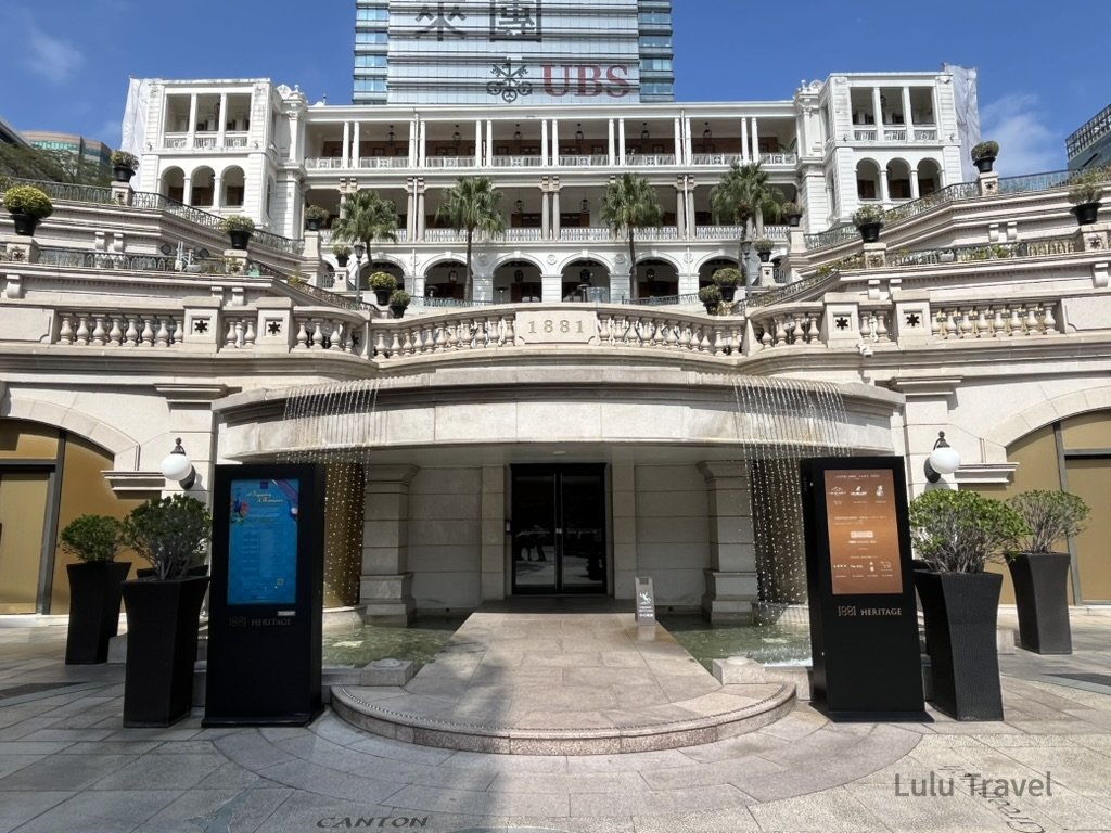 香港中環 1881 Heritage 歷史建築正門外觀，白色殖民風格拱廊與階梯噴泉構成對稱立面，展現中環經典地標與現代商業大樓交融的城市景觀