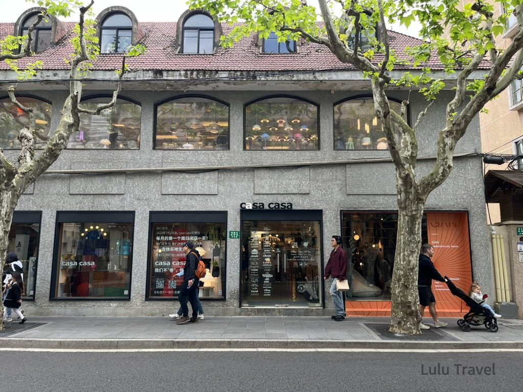 上海城市漫步會看見街頭林蔭大道旁的 casa casa 店面外觀，灰色建築立面搭配大片窗景