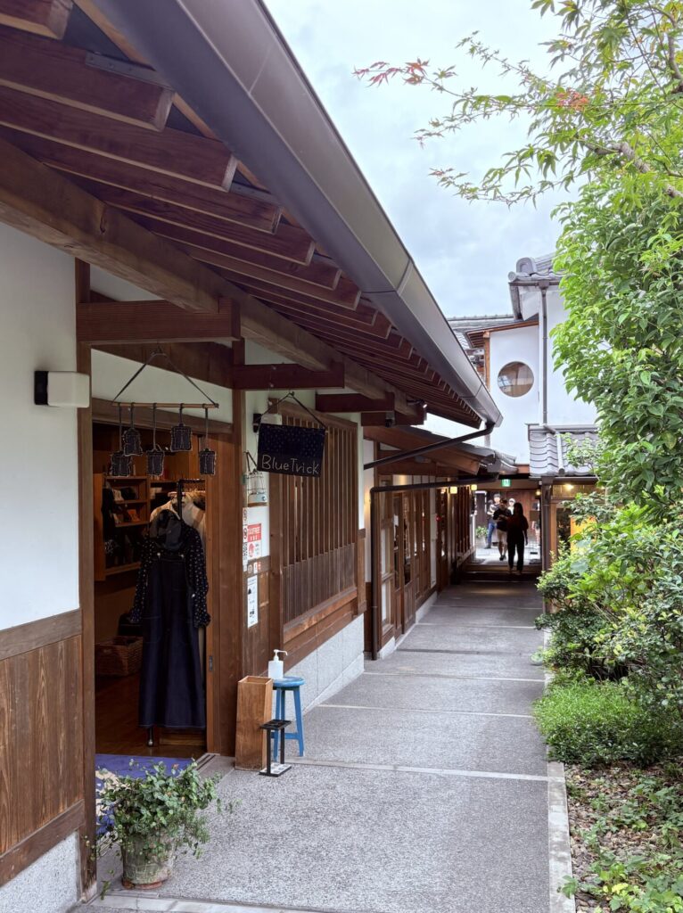 倉敷美觀地區|日本倉敷的 1 段散步旅遊記錄 日本岡山倉敷美觀地區,傳統町屋改建的商店街巷道,木造建築與綠意交錯,遊客沿著步道散步