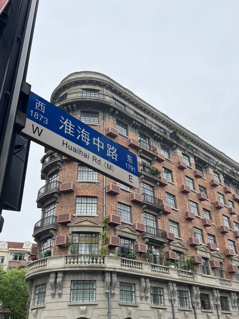 上海淮海中路街口的租界時期紅磚弧形建築，外牆排列整齊的窗格與陽台，展現老上海城市立面