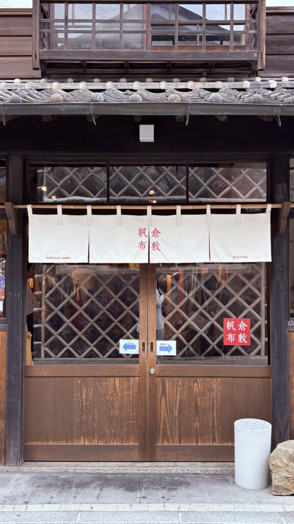 倉敷美觀地區|日本倉敷的 1 段散步旅遊記錄 日本岡山倉敷美觀地區的傳統町屋店家外觀,木造建築搭配白色門簾與格子拉門,呈現江戶風格的歷史街景