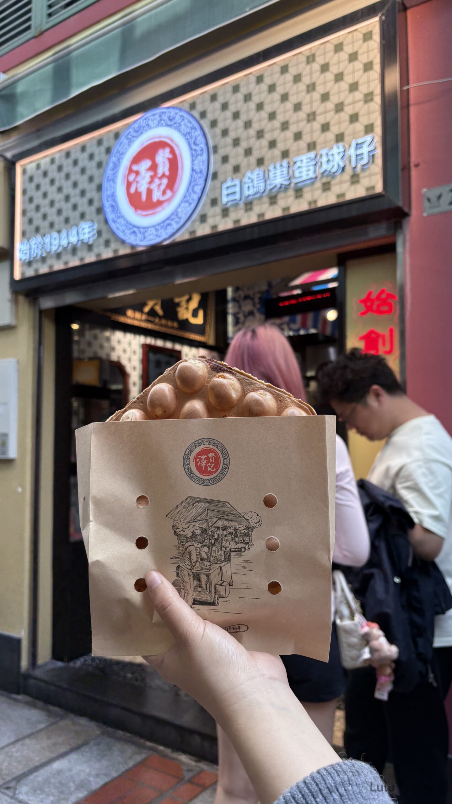 澳門必吃美食雞蛋仔，手拿熱騰騰的雞蛋仔站在澳門老字號小吃店門口，感受官也街周邊的人氣街頭美食文化