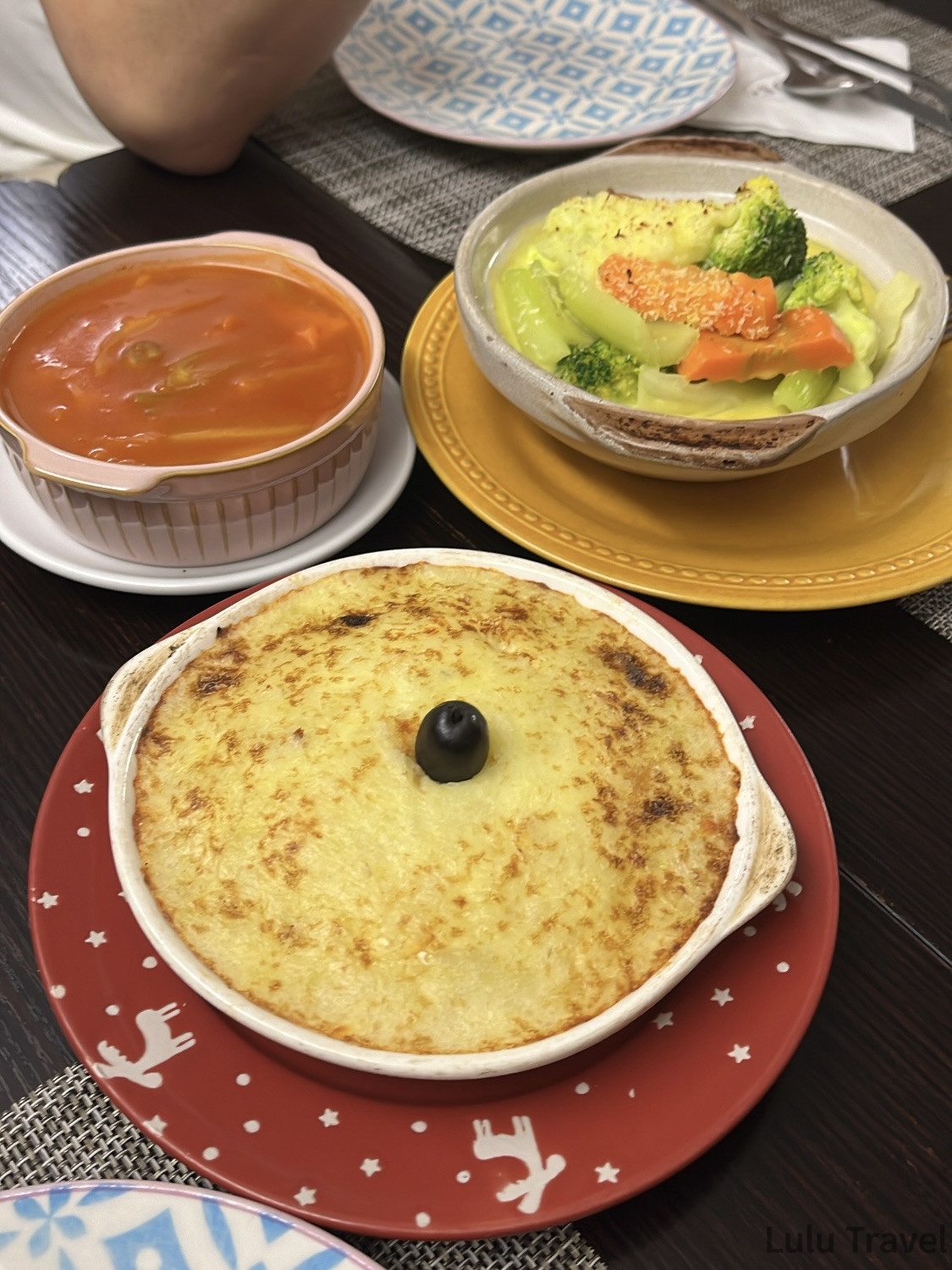 澳門葡式料理晚餐，前景為葡式焗馬鈴薯泥配黑橄欖，後方為番茄湯與清炒蔬菜