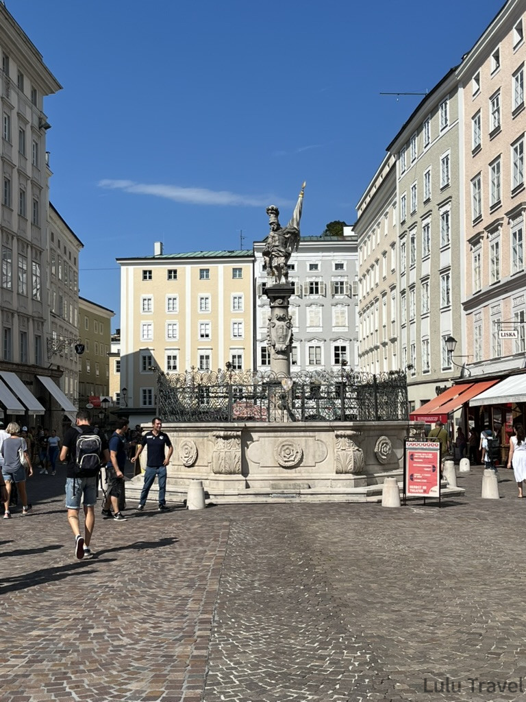 薩爾斯堡老城廣場 Alter Markt，中央矗立巴洛克風格雕塑噴泉，四周被歷史建築圍繞