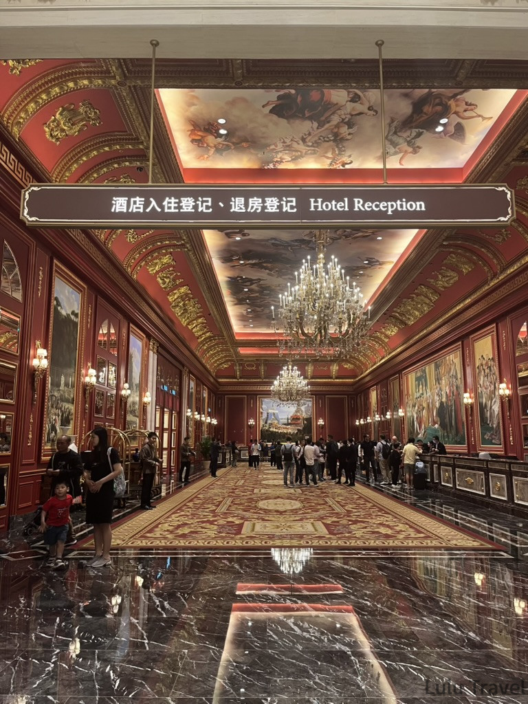 澳門倫敦人酒店深紅配金大廳，對稱掛畫與水晶吊燈構成富麗堂皇的歐式宮廷風格走廊