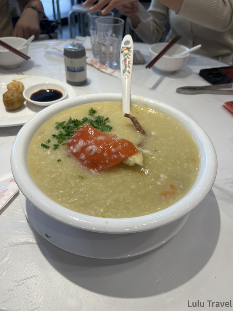 澳門官也街附近餐廳的蟹肉粥，整隻蟹鉗置於細滑粥底上，撒蔥花點綴
