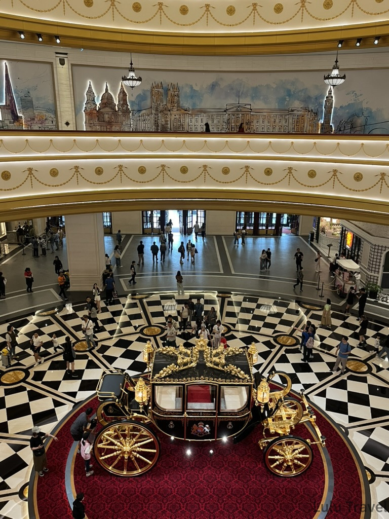 澳門倫敦人酒店大廳俯瞰，黑白棋盤格地板中央展示金色皇家馬車，四周牆面繪有倫敦地標壁畫
