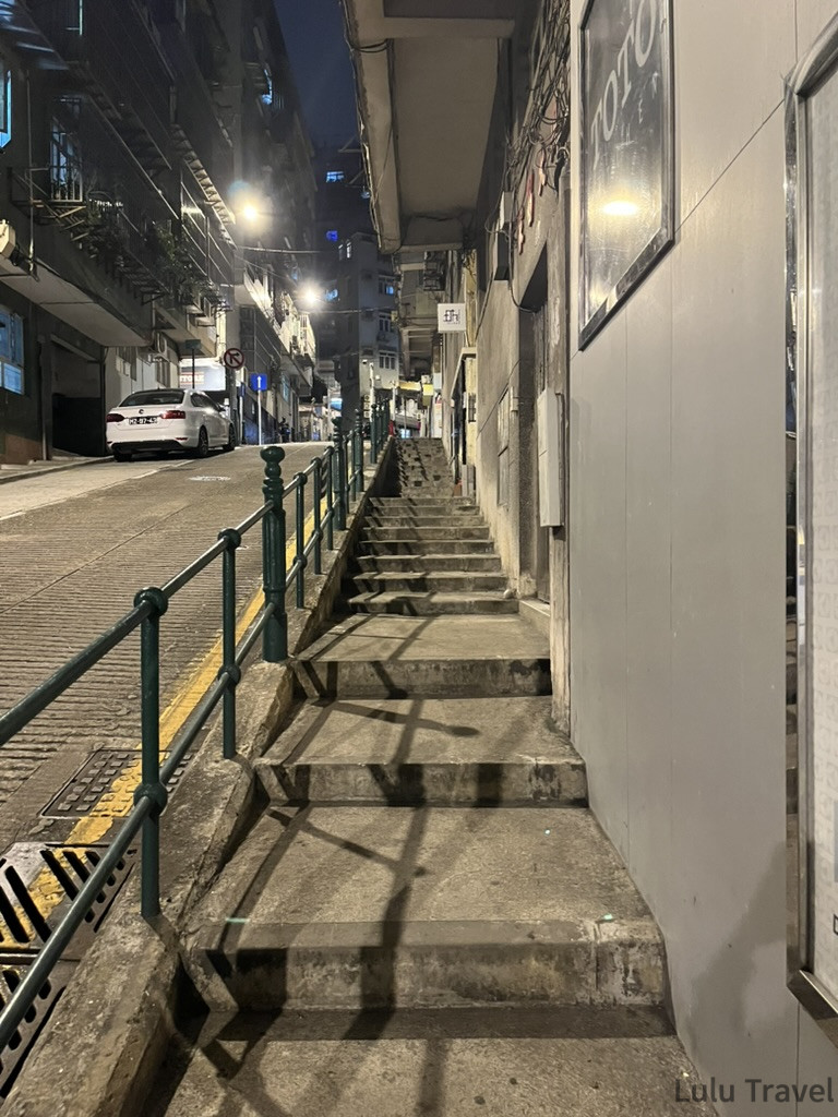 澳門半島夜晚的石階小路，路燈照亮兩側舊建築立面，展現澳門老城區的日常街景