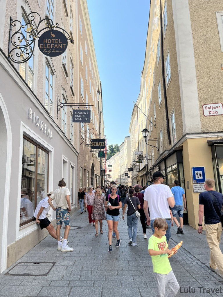 薩爾斯堡旅遊必逛 Getreidegasse 商業街，兩側歷史建築掛著各式鍛鐵招牌，遊客漫步其間