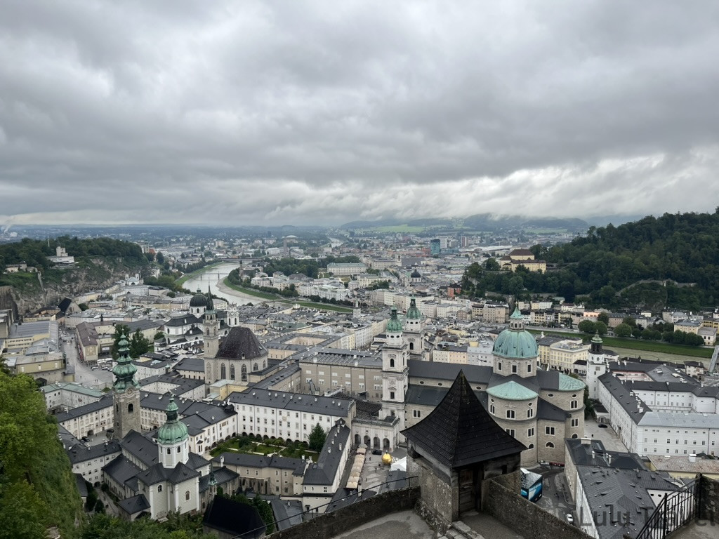 從霍亨薩爾斯堡城堡俯瞰薩爾斯堡旅遊全景，薩爾察赫河蜿蜒其中，多座教堂圓頂點綴城市天際線