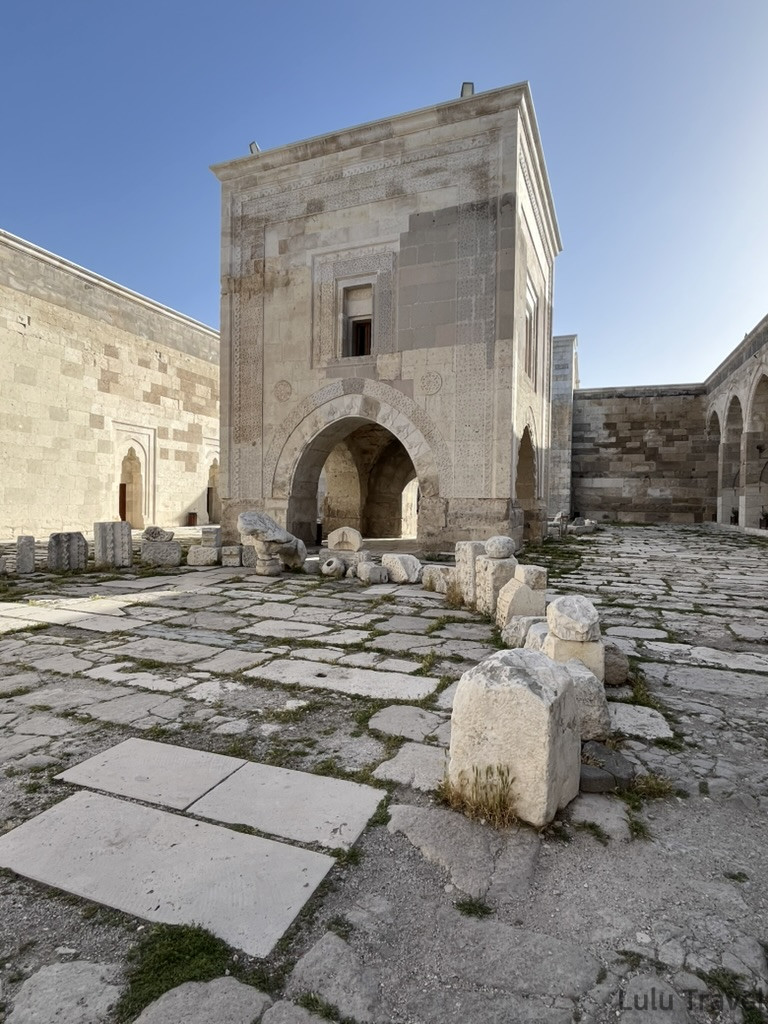 驛站的石板廣場景象，白色石製路面與拱形建築遺跡，顯示古代休憩點的建築形式